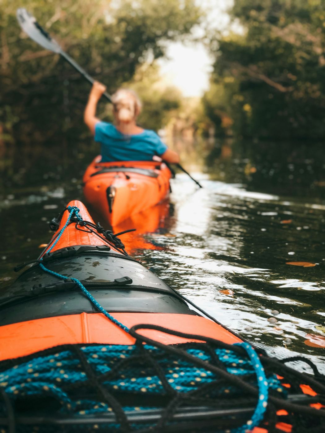Une femme en kayak sur une rivière bordée d’arbres